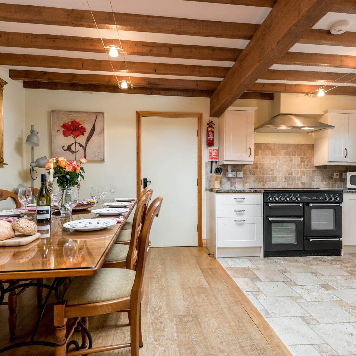large dining table set for a meal and a kitchen area with range oven 