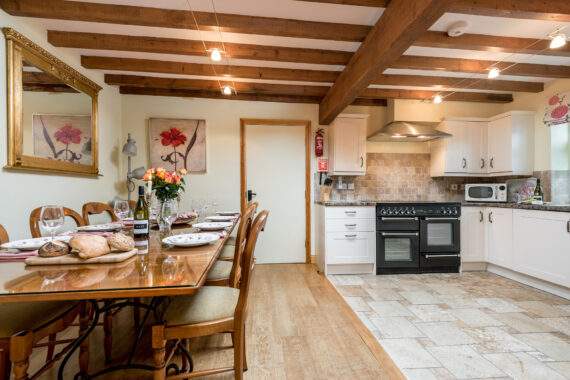 large dining table set for a meal and a kitchen area with range oven 