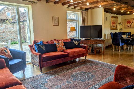 comfortable sofas and a big tv in the living room with a dining table in the background 