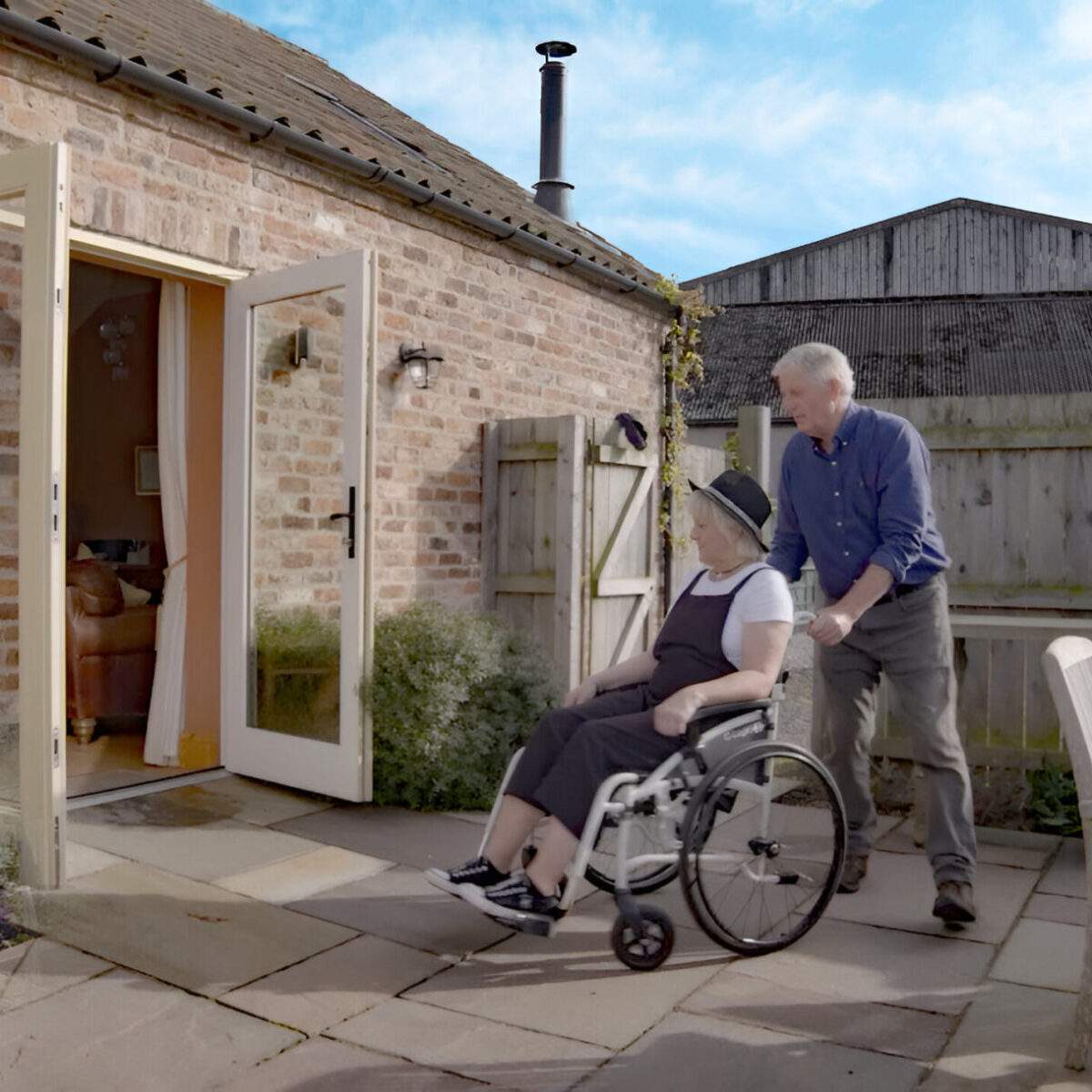 Courtyard Wheel Chair access man pushing a woman in a wheelchair into courtyard cottage from the garden