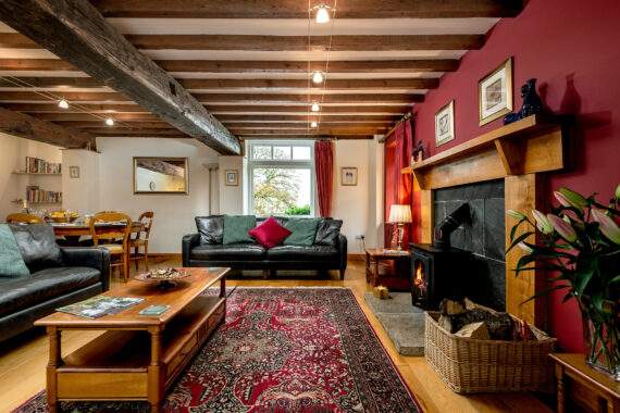 Living room with a wood burner, comfortable sofas and dining area in the corner