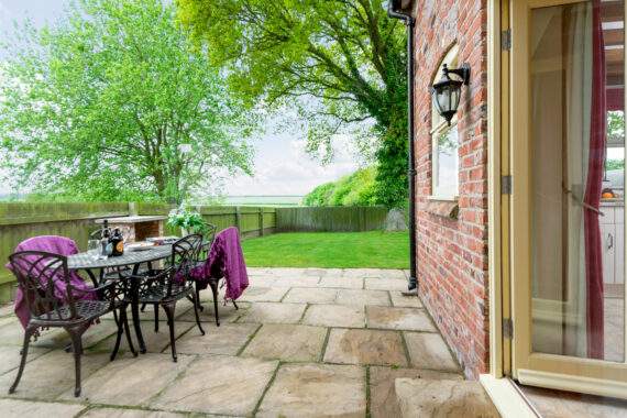 French doors from the kitchen lead out onto the patio where there is a table and chairs for outside dining 