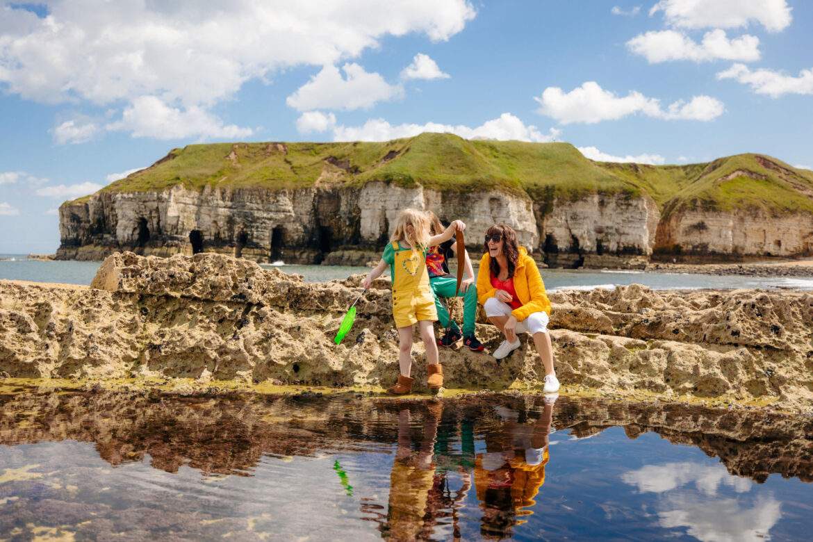 family rockpooling with cliffs in the backgroud
